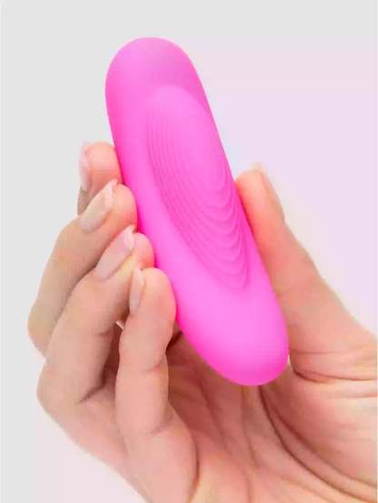 Pink silicone tool held in a hand against a white background