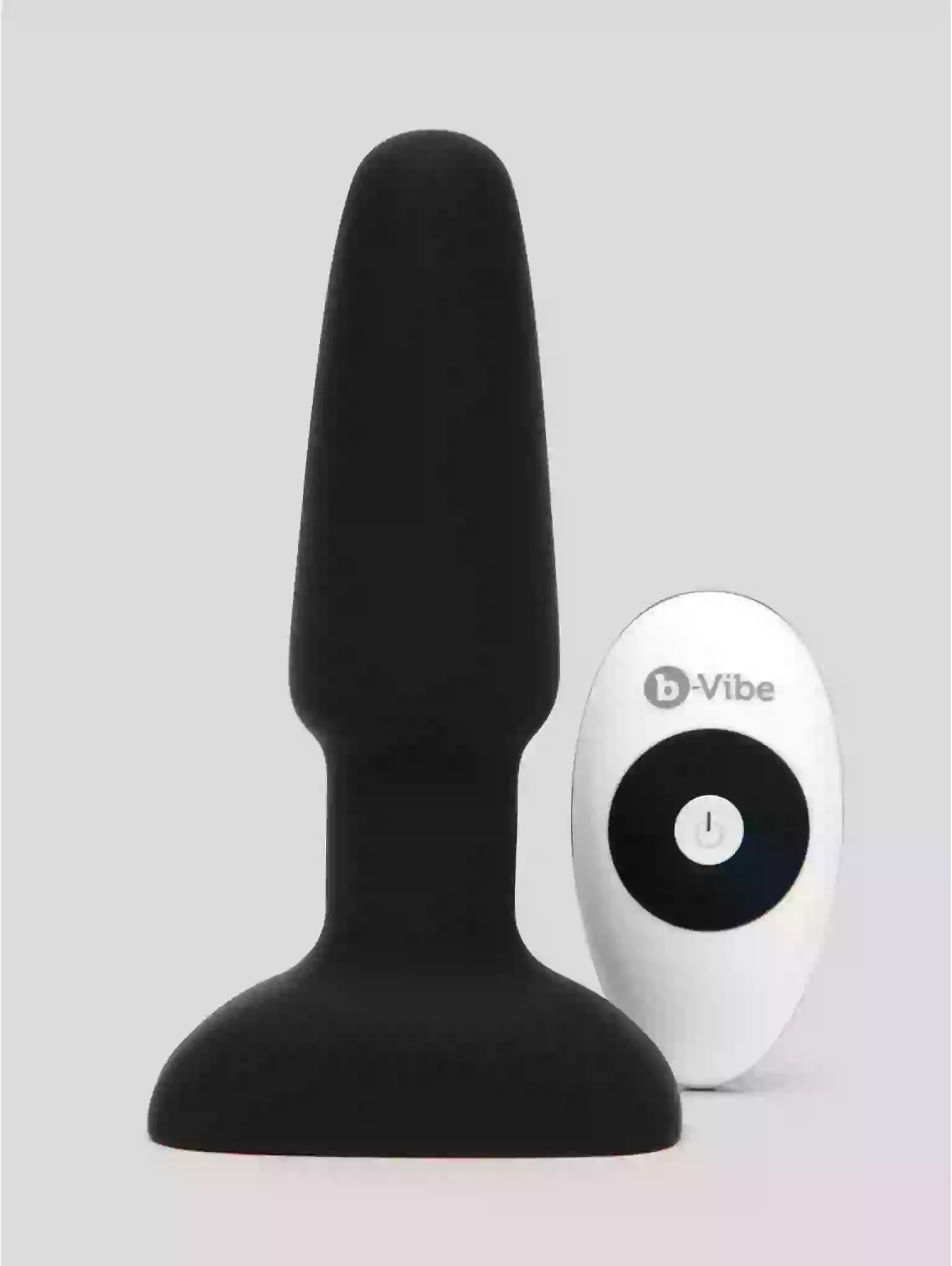 Black silicone butt plug and white remote control on a light gray background