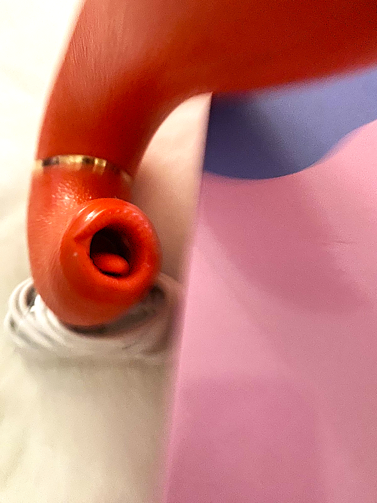 Close-up of a red earbud with a white cable on a blurred background
