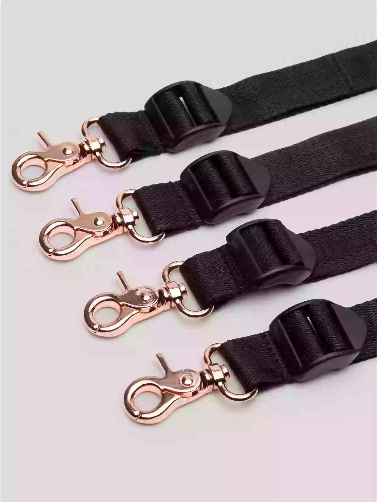 Black straps with rose gold hardware on a light gray background