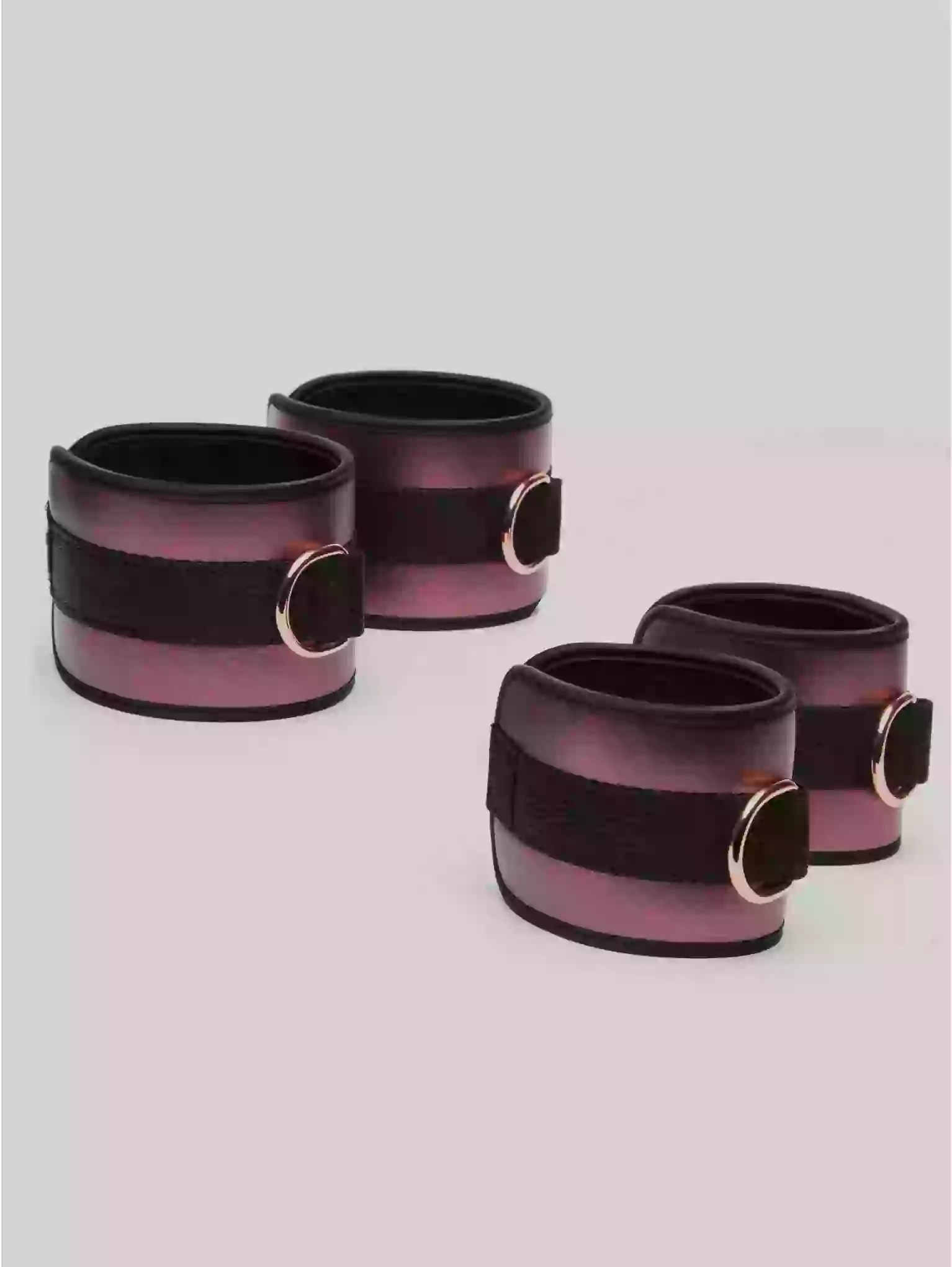Set of four black and pink ceramic cups with gold accents on a light gray background