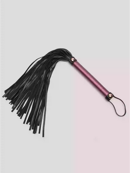 Black leather flogger with pink handle on a light gray background