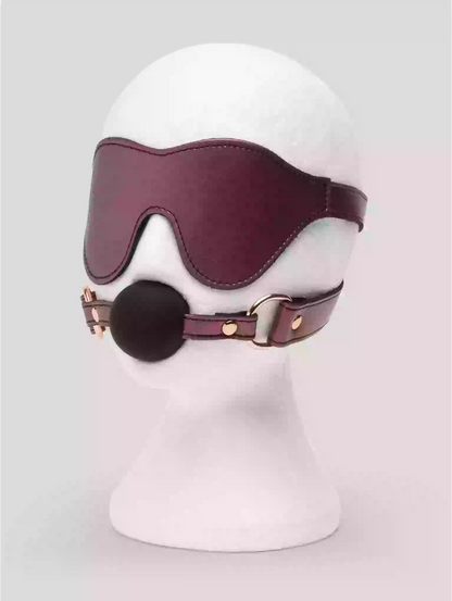Leather muzzle and collar on a mannequin head against a light gray background