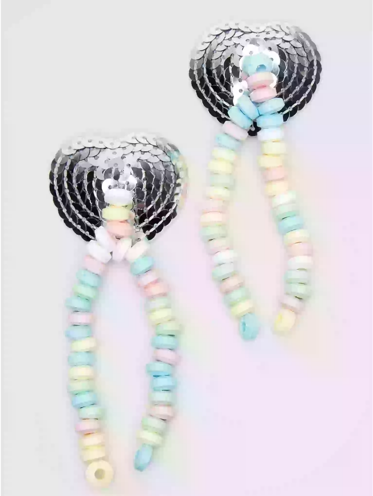 Pair of earrings with pastel beads and sequin hearts on a light background