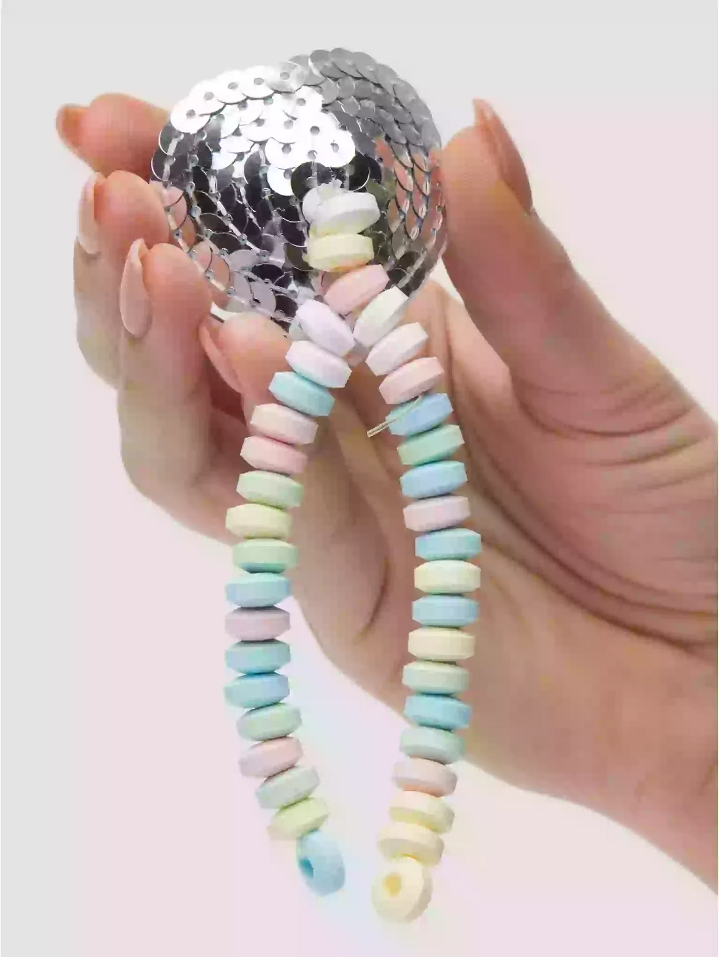 Hand holding a colorful beaded keychain with a silver sequin ball on a white background