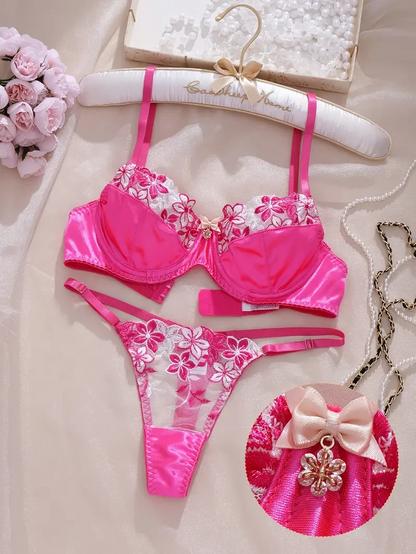 Pink floral bikini set on a hanger with decorative elements.