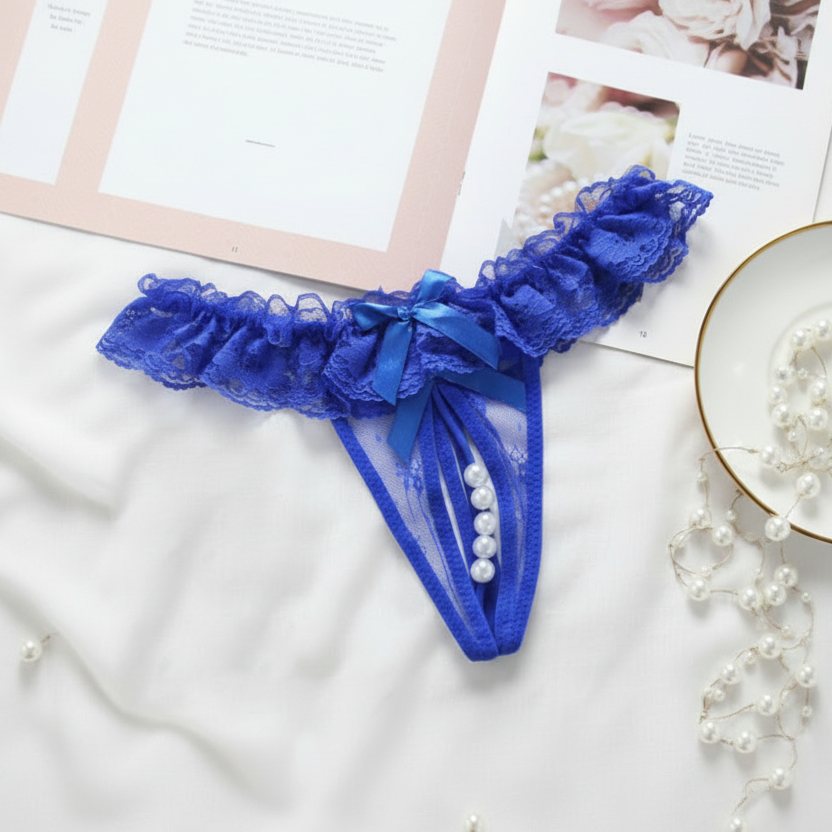 Blue lace thong with pearls on a white surface with magazines and pearls.