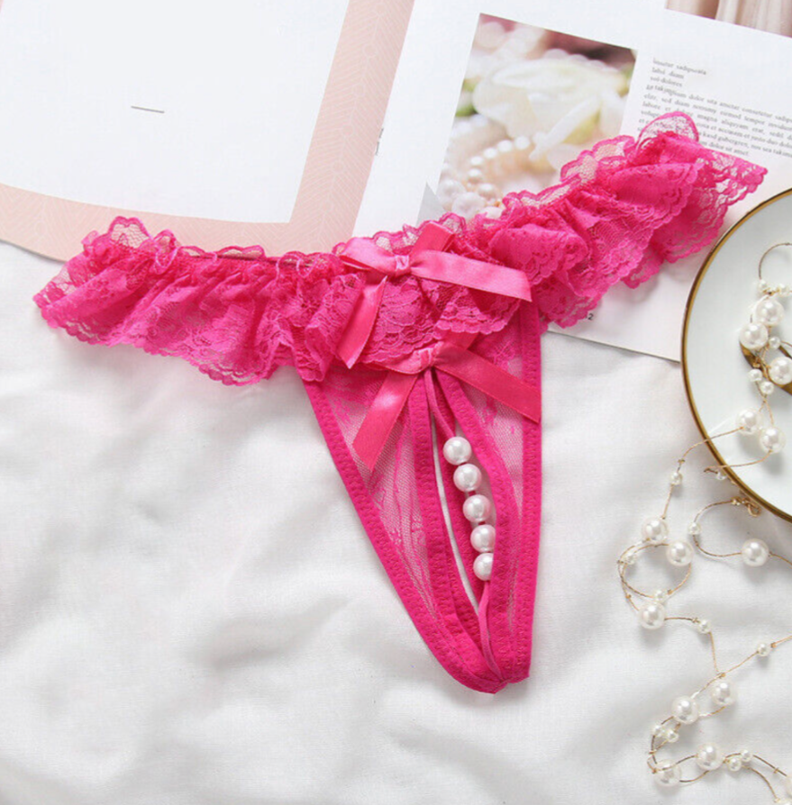 Pink lace lingerie set with pearls on a white surface