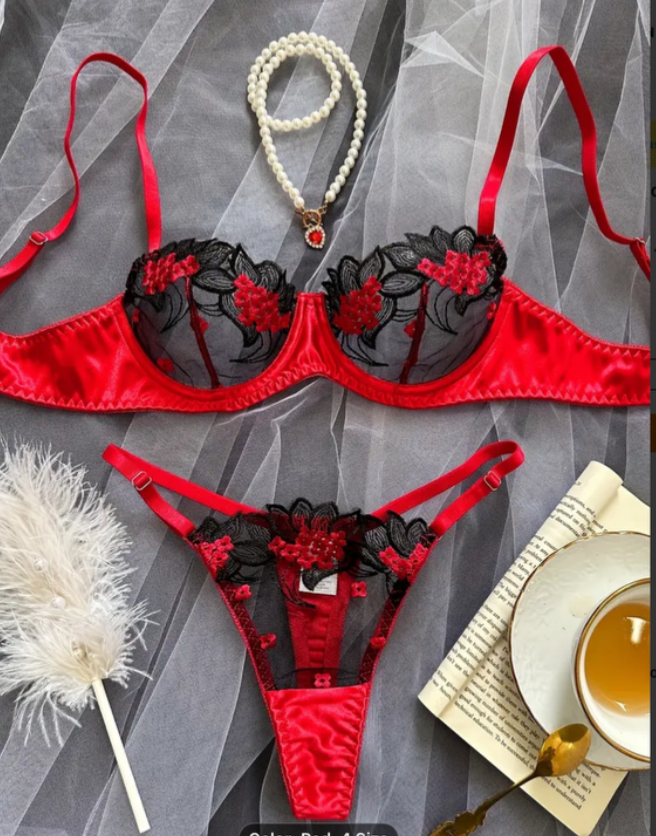 Red and black lingerie set with a pearl necklace on a gray background
