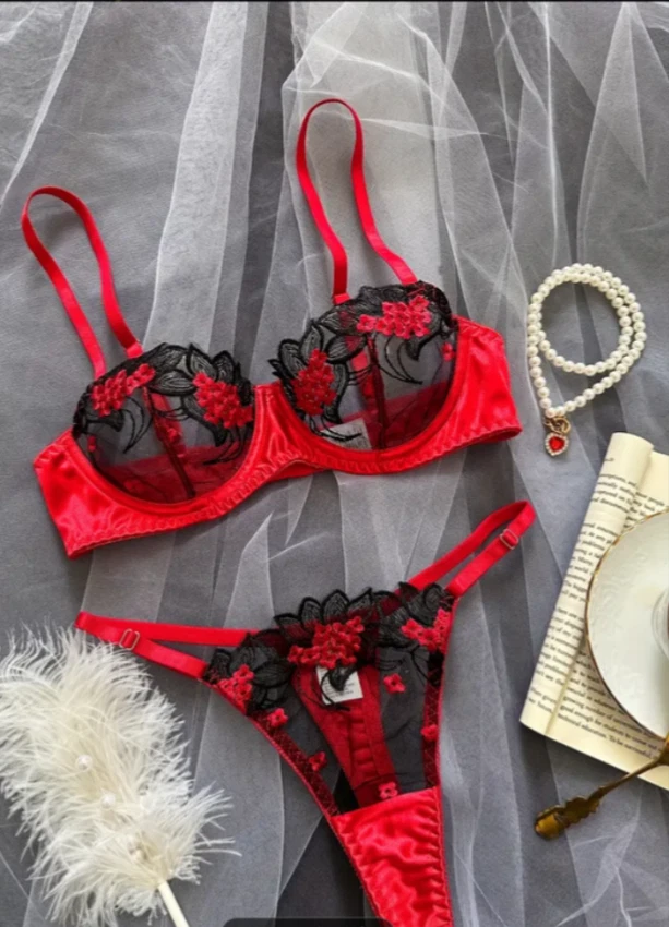 Red and black lace lingerie set on a gray background with decorative items.