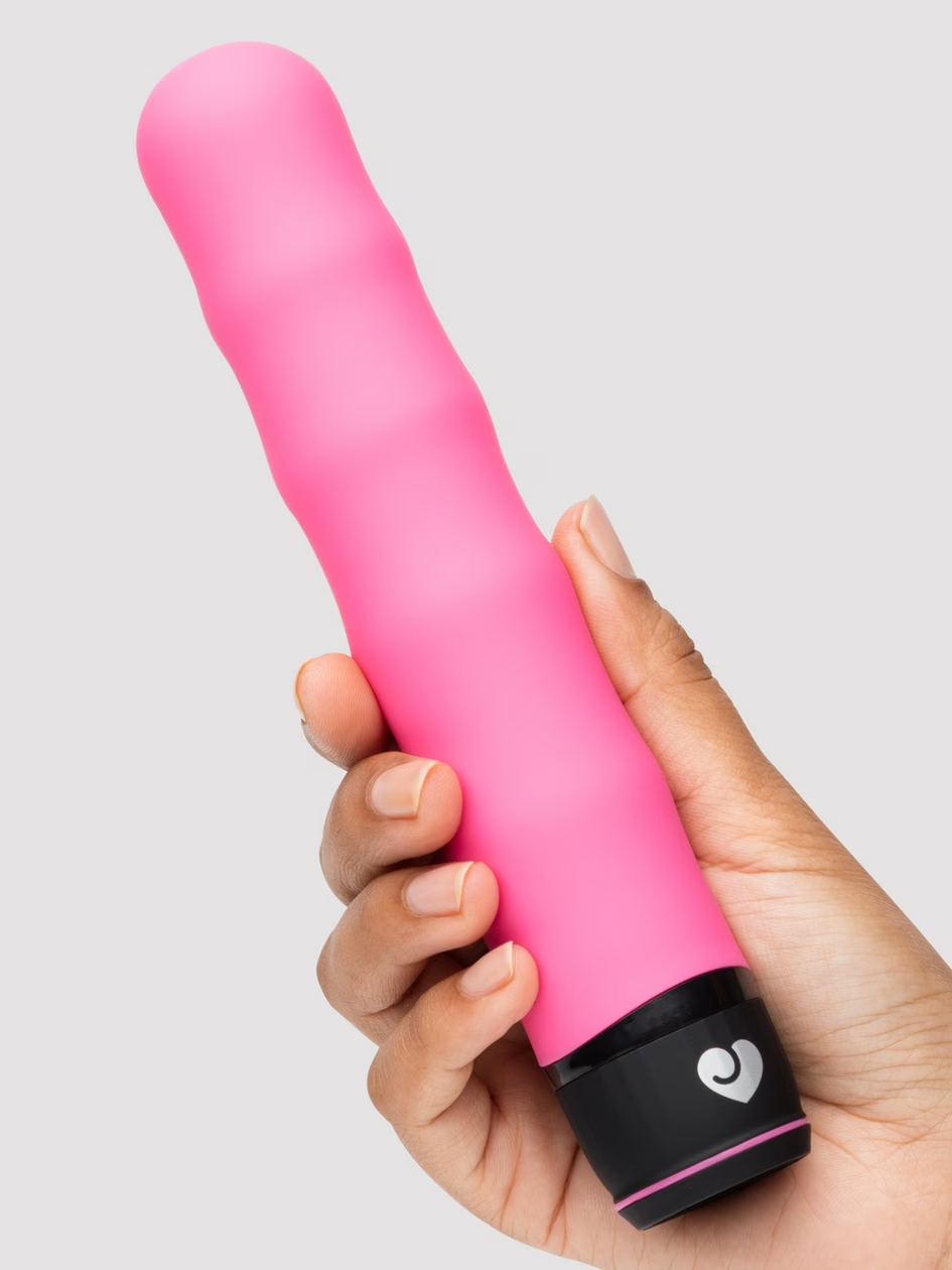Pink and black electronic device held in a hand against a light gray background