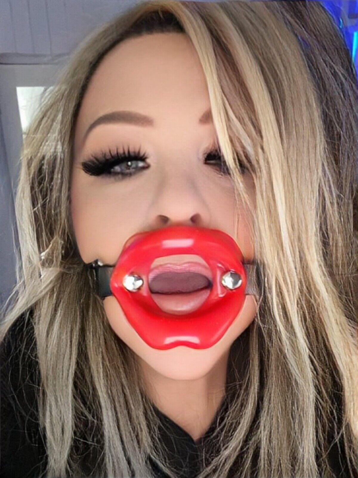Person wearing a red lip-shaped accessory with a black strap.