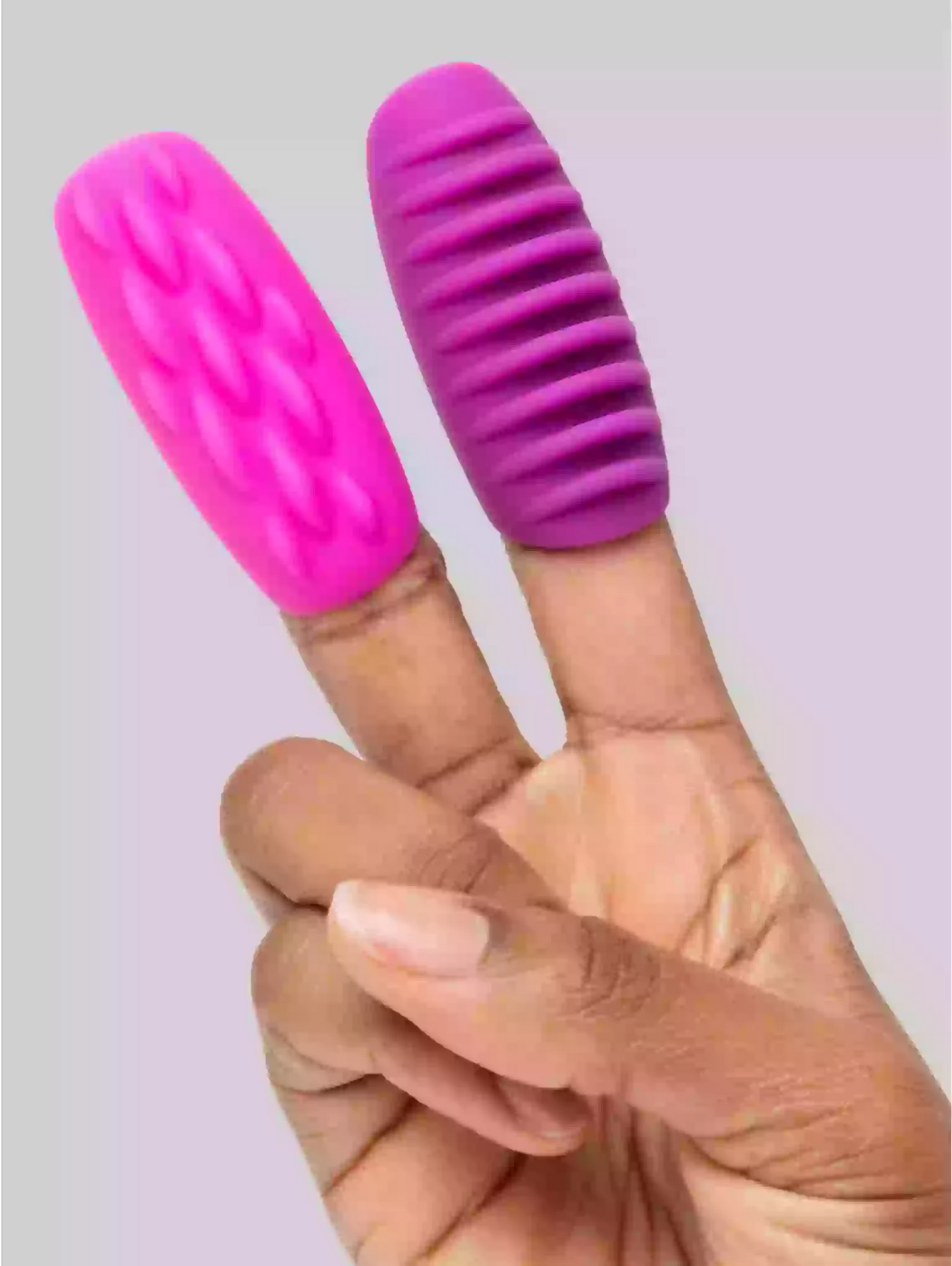 Pink and purple finger exercisers on a person's fingers against a light background