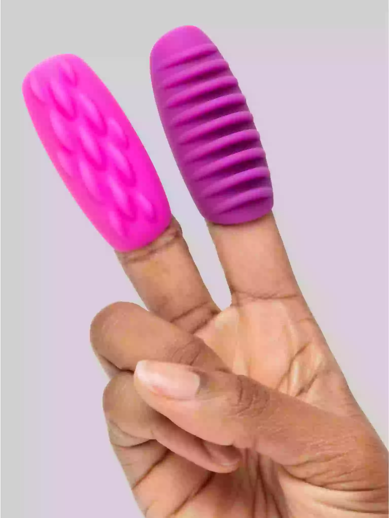 Pink and purple finger exercisers on a person's fingers against a light background