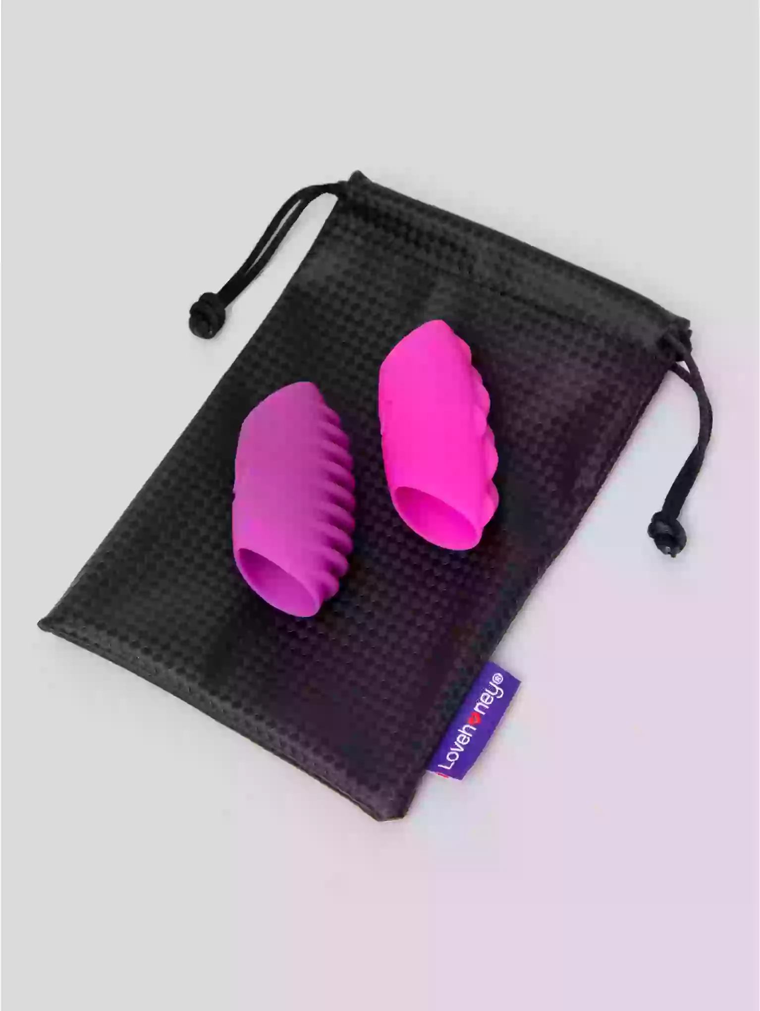 Two pink silicone products in a black drawstring bag on a light gray background