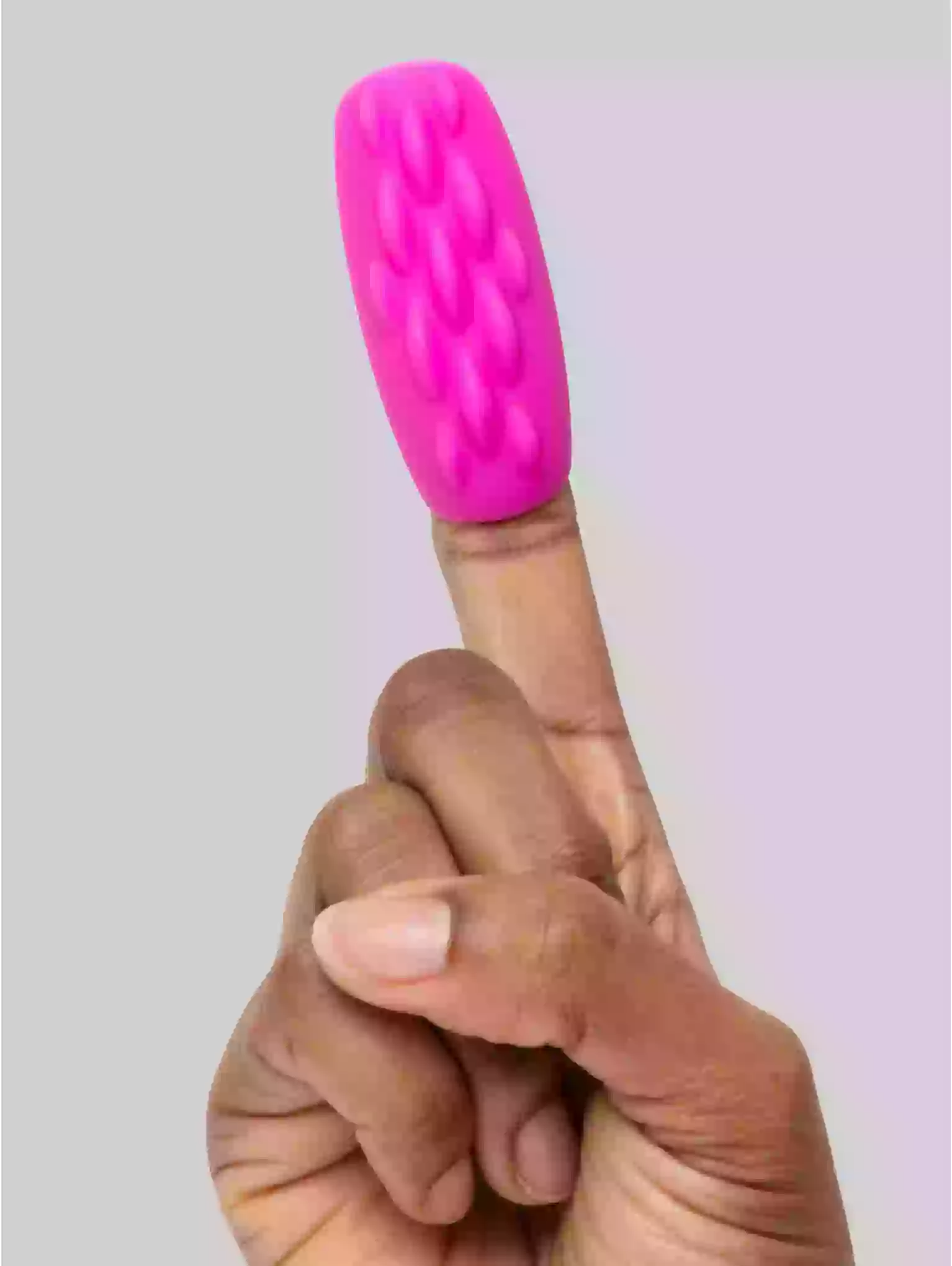 Pink silicone finger sleeve on a finger against a light gray background