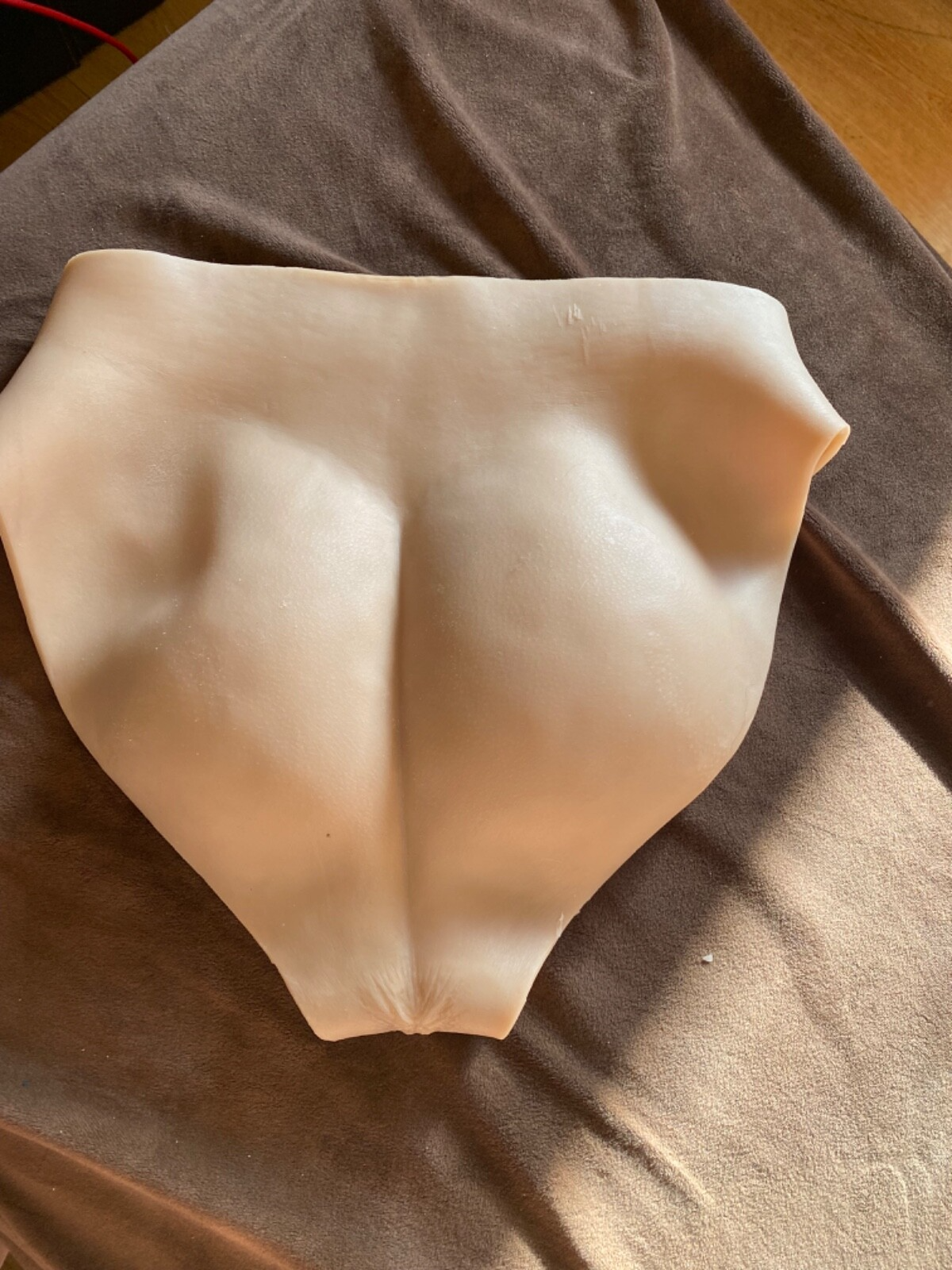 Silicone mold shaped like a breast on a brown surface