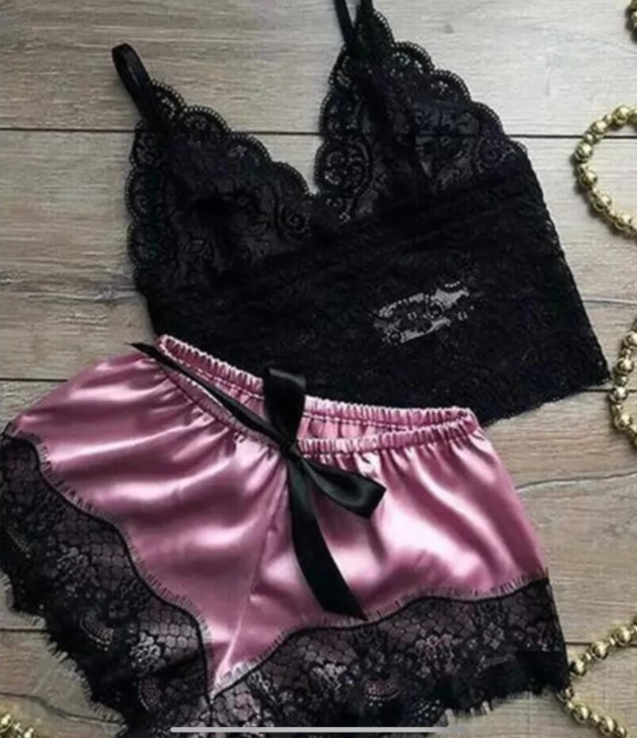 Black lace bra and pink satin shorts with a black bow on a wooden surface.
