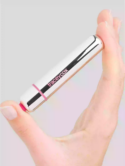 Hand holding a Tracey Cox lip balm against a light gray background
