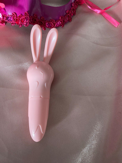 Pink rabbit-shaped object on a textured surface with a pink headband in the background.