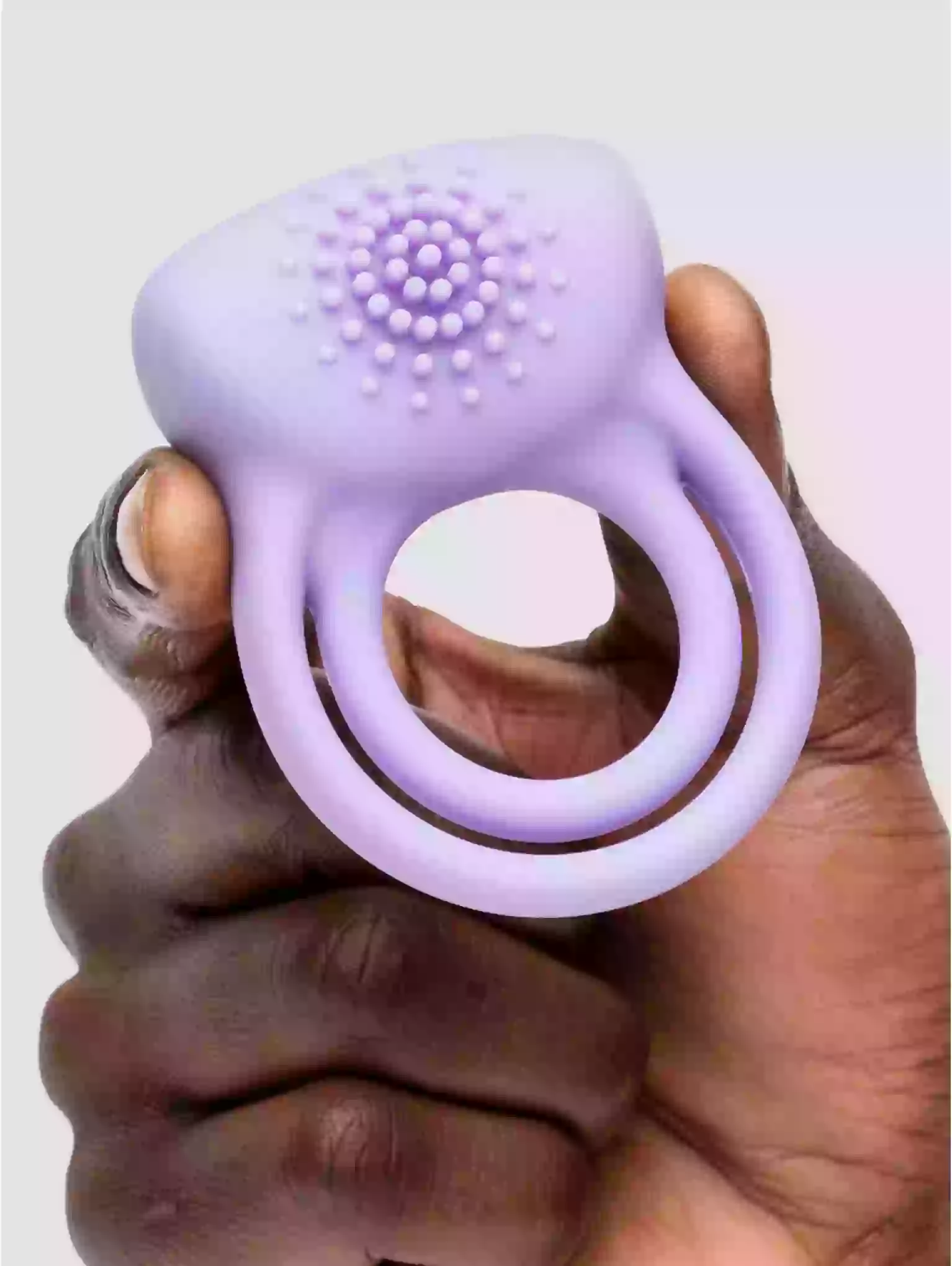 Purple silicone ring with textured surface held in a hand against a light background
