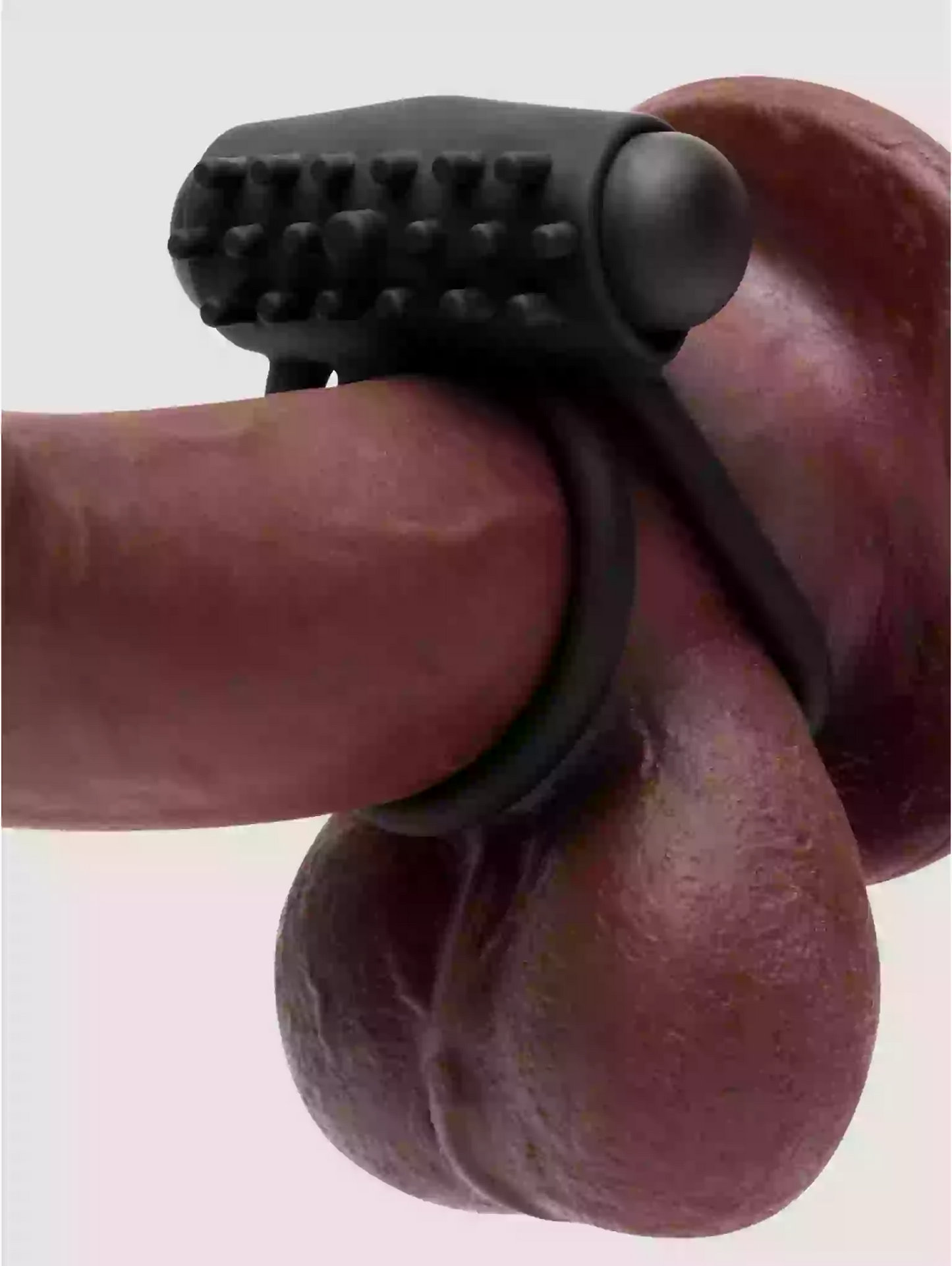 Black silicone ring with textured design on a finger against a light gray background