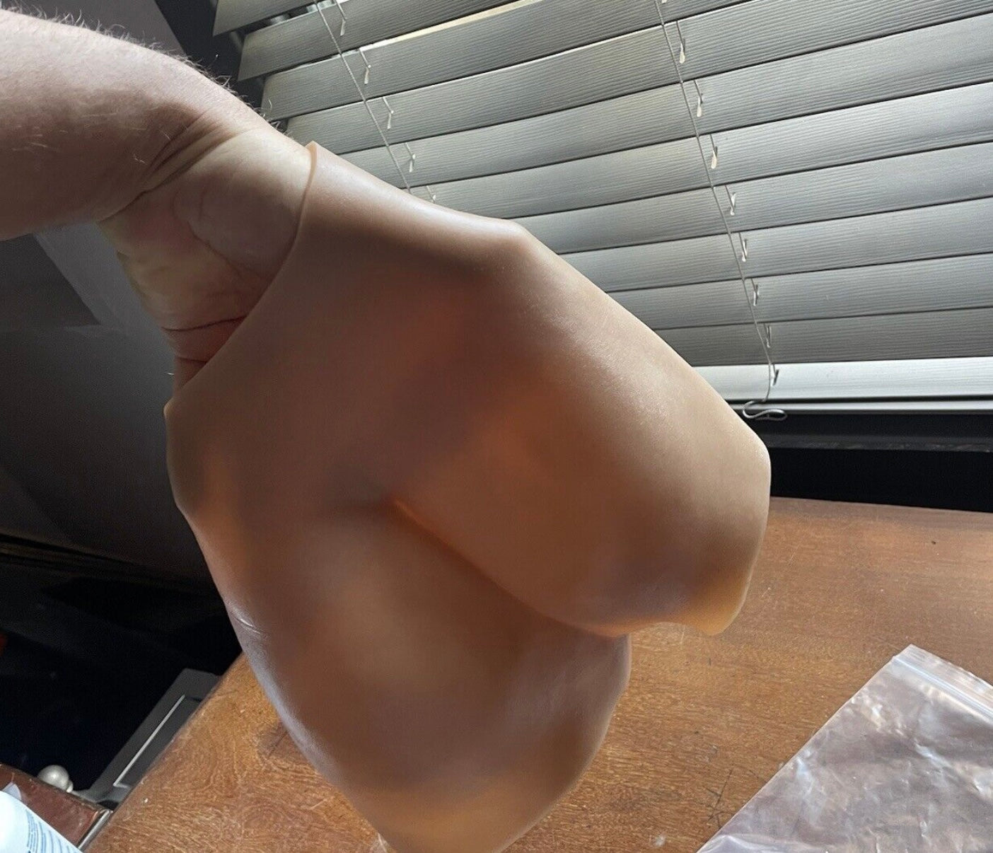Hand wearing a latex glove with a window blind in the background