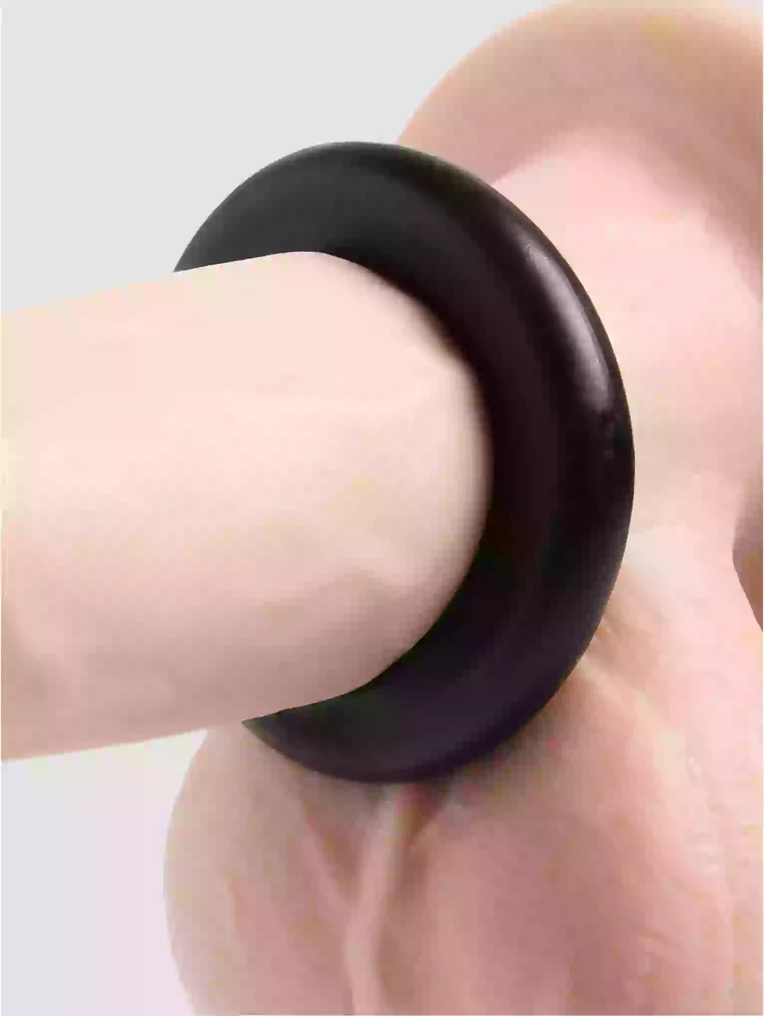 Black ring on a finger against a light background