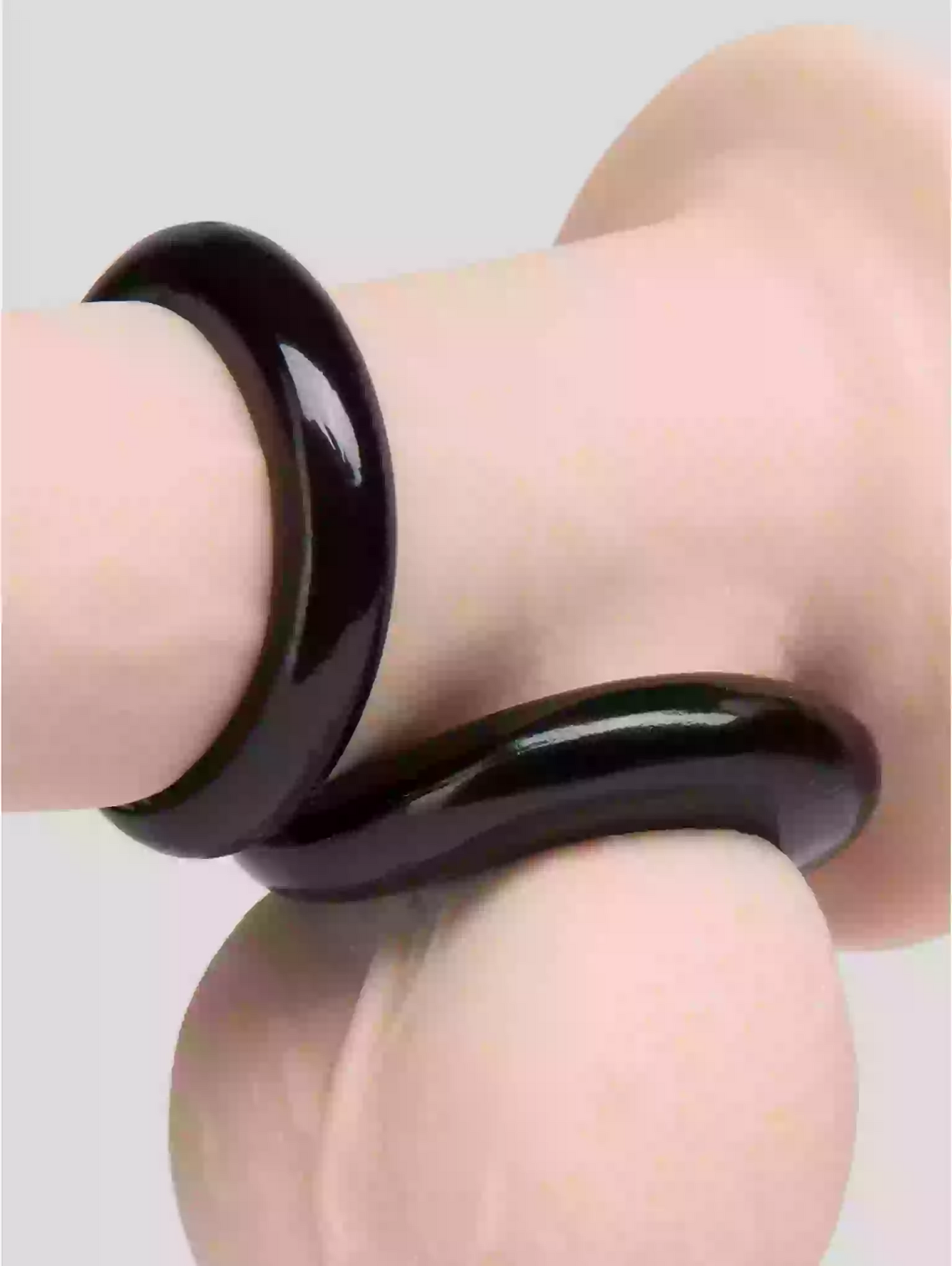 Black bangle on a light skin arm against a neutral background