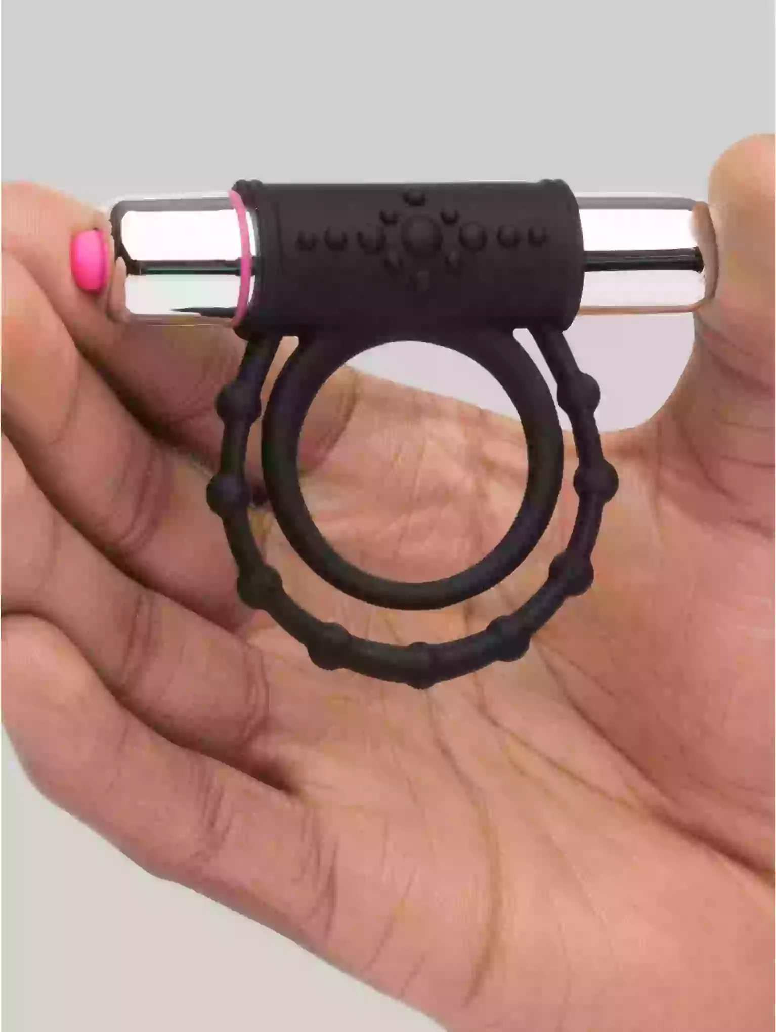 Black ring with a metallic core held in a hand against a neutral background