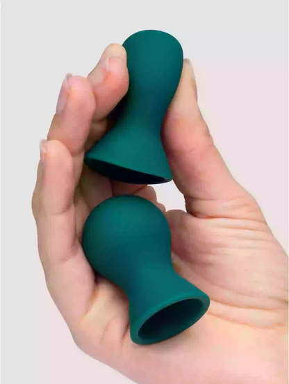 Teal silicone cupping device held in a hand against a plain background
