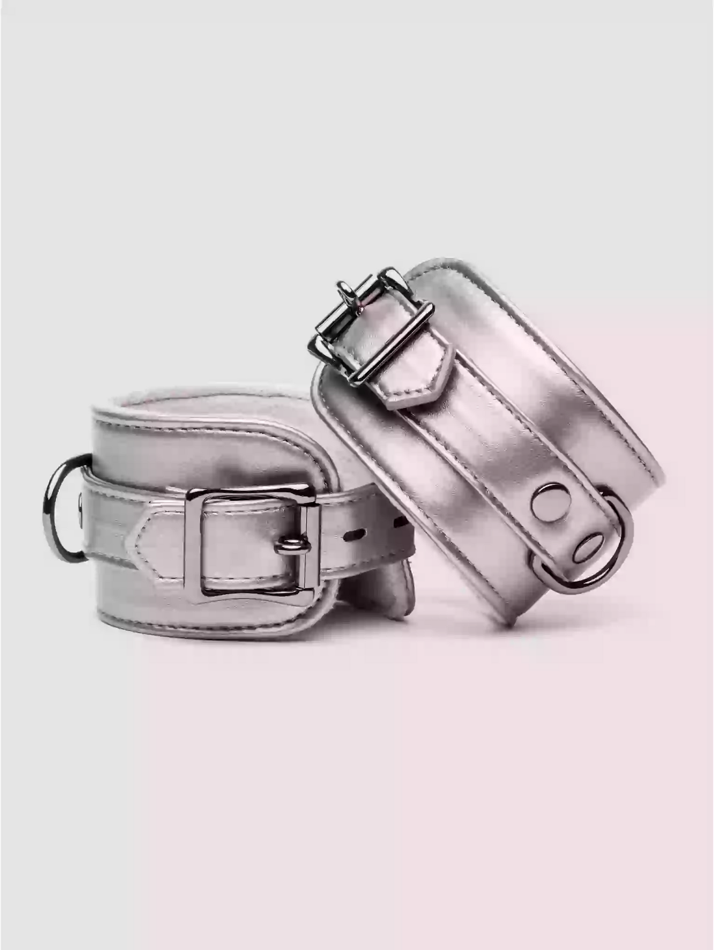 Two metallic silver dog collars on a light pink background