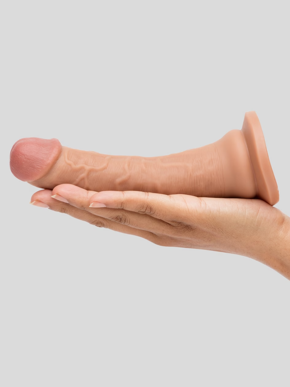 Hand holding a small brown object against a light gray background