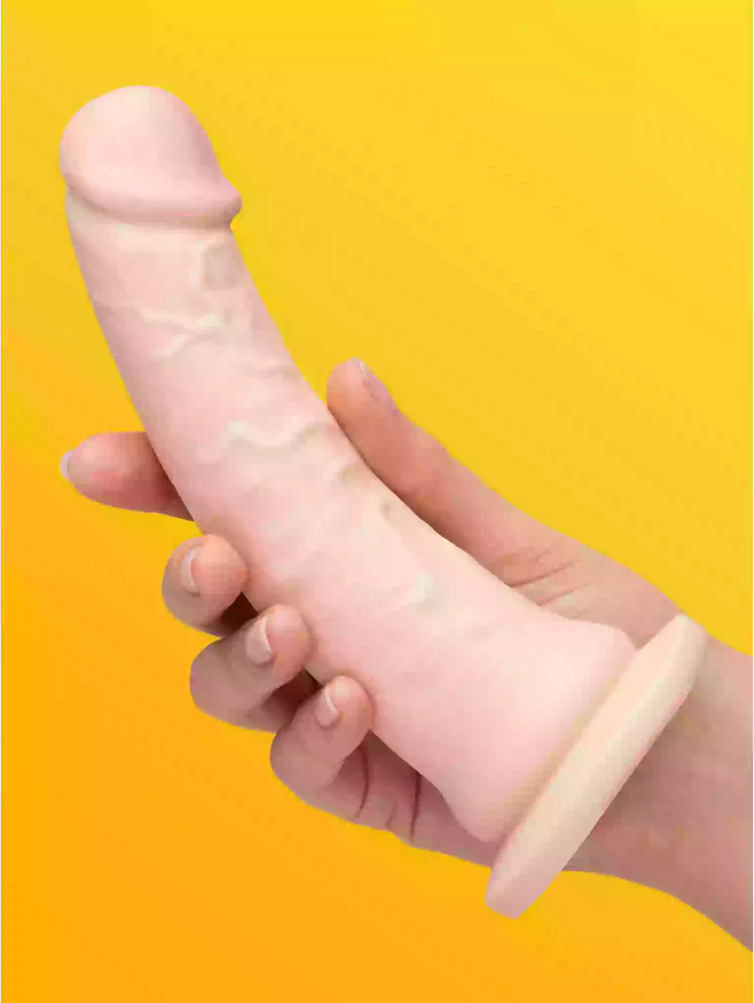Hand holding a pink silicone product against a yellow background