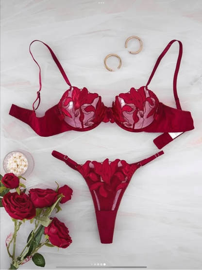 Red lingerie set with floral details on a white background, accompanied by red roses.