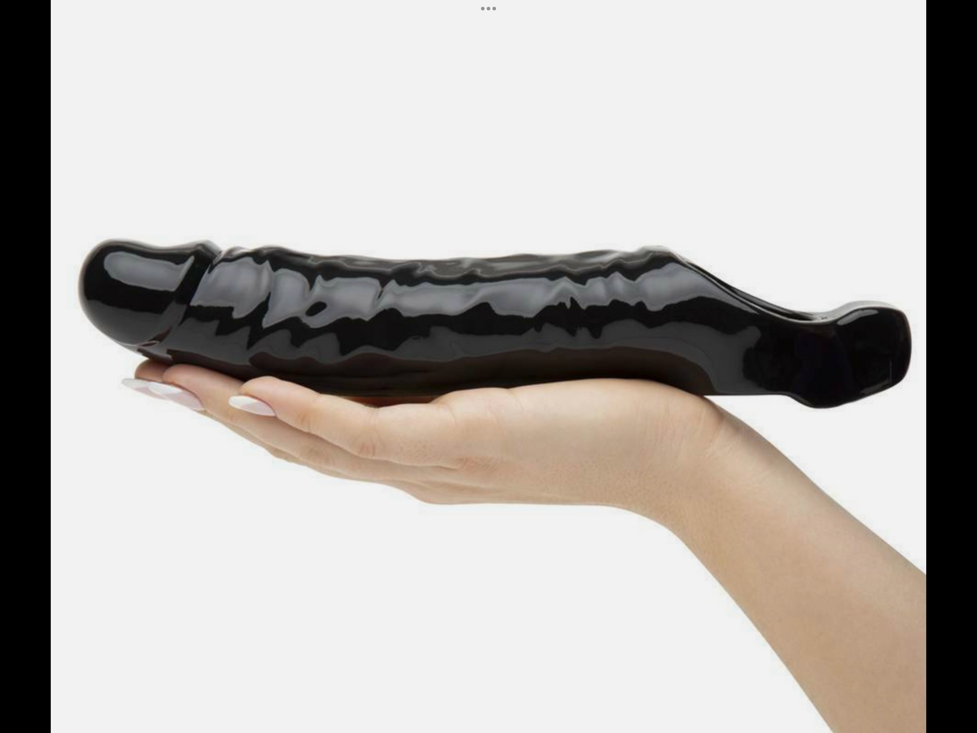 Hand holding a large black ceramic object against a white background