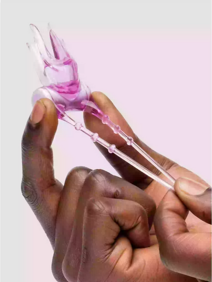 Hand holding a pink and clear hair tie against a light purple background