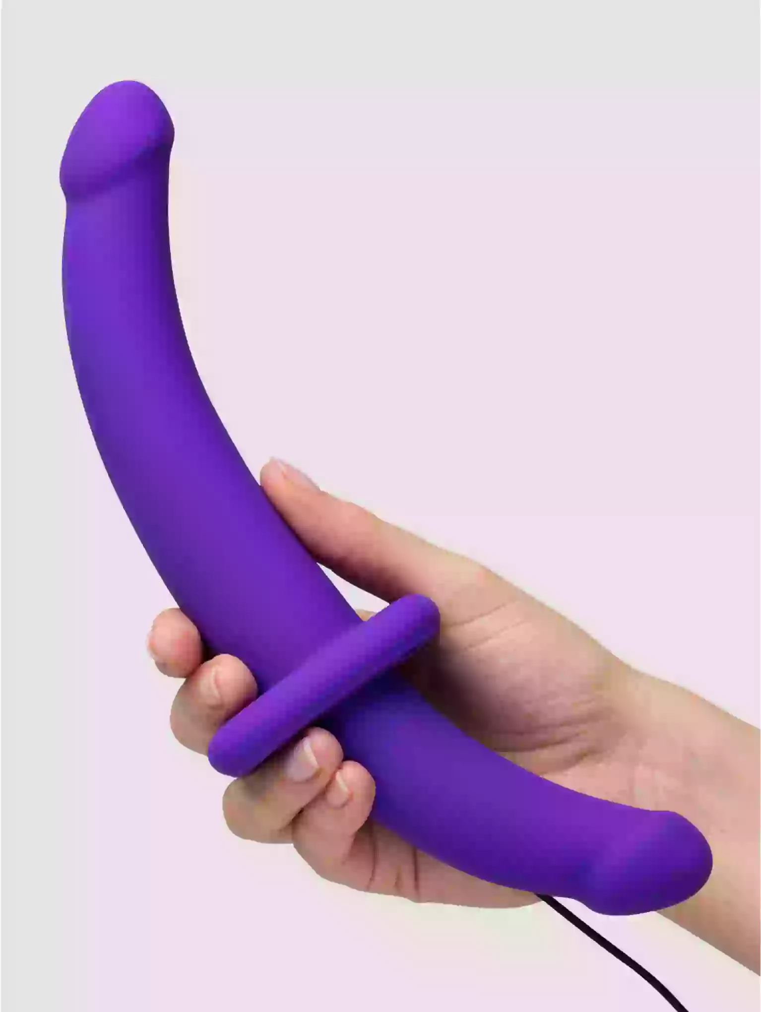 Purple curved object held in a hand against a light purple background