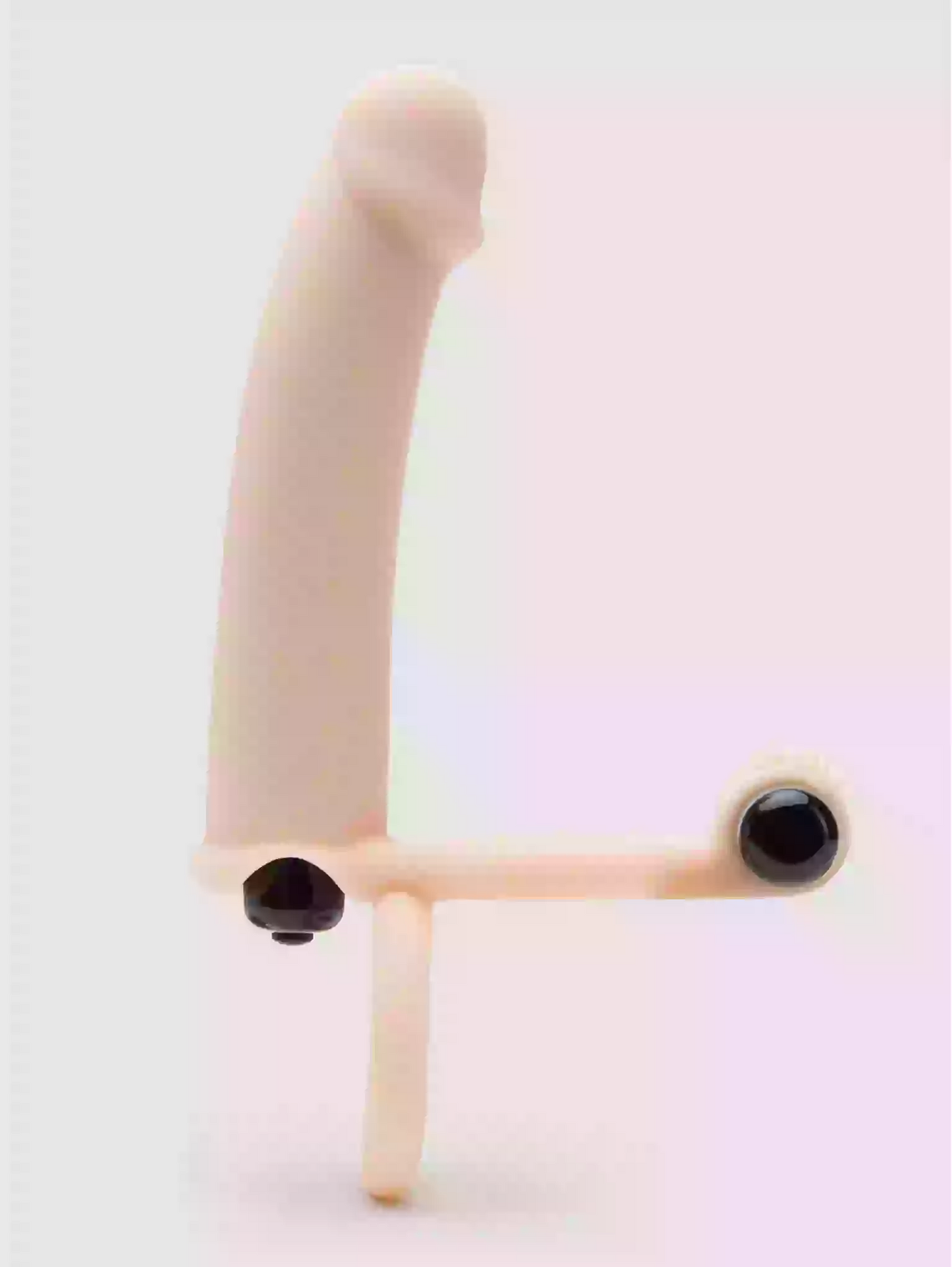 Sculptural object with curved beige arm and black circular elements on a light pink background