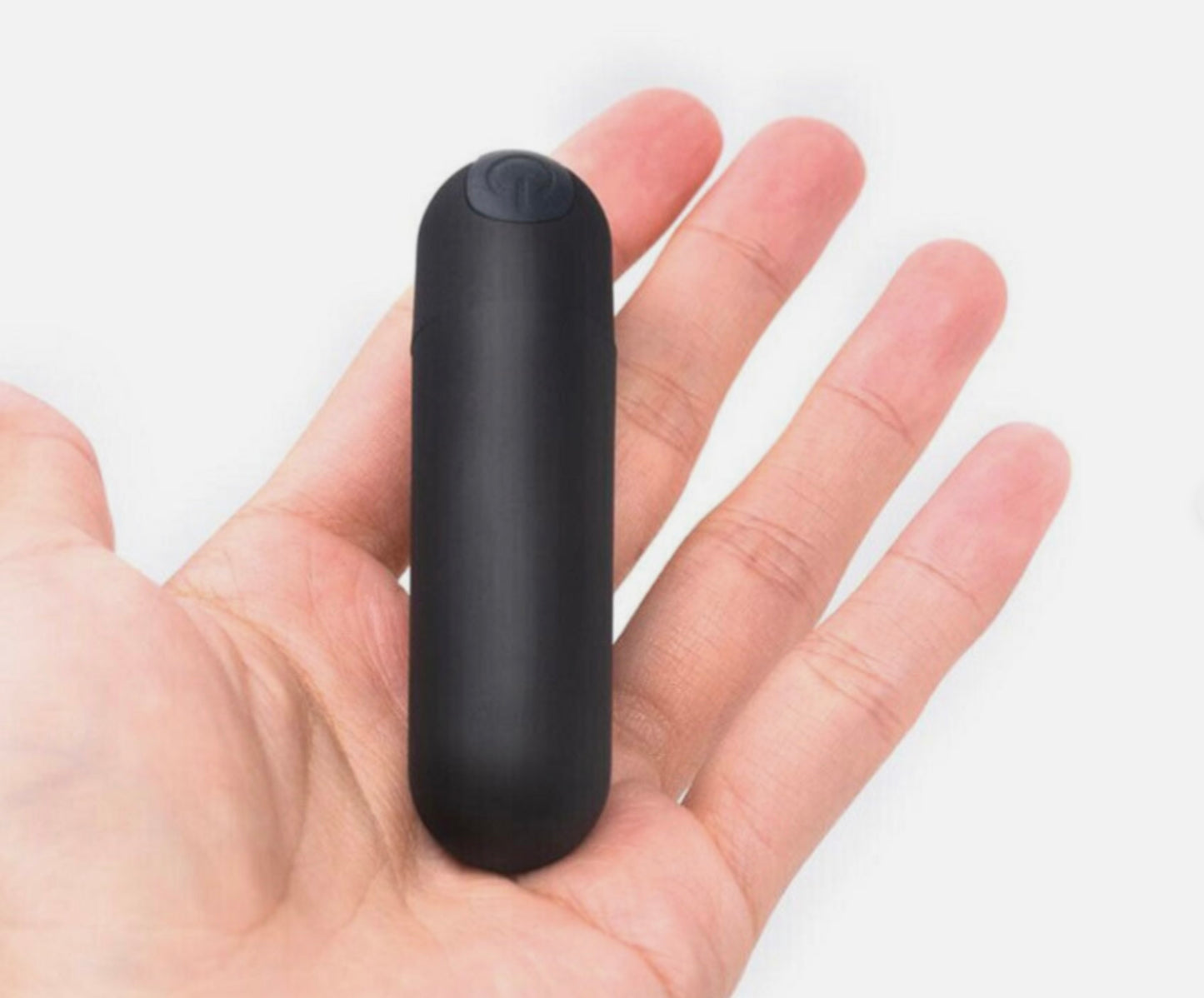 Black cylindrical object held in a hand against a white background