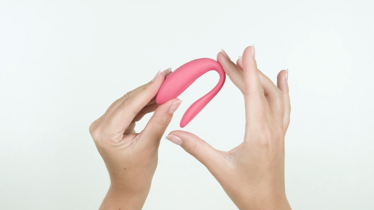 Pink curved object held between two hands against a white background