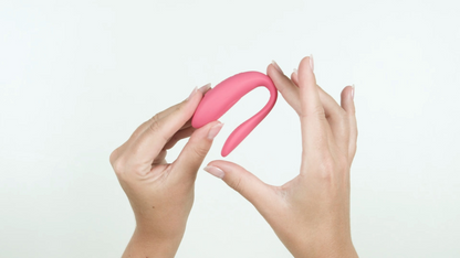 Pink curved object held between two hands against a white background