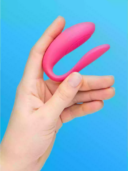 Pink curved object held in a hand against a blue background