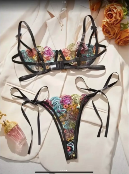 Black lingerie set with floral embroidery on a white surface.