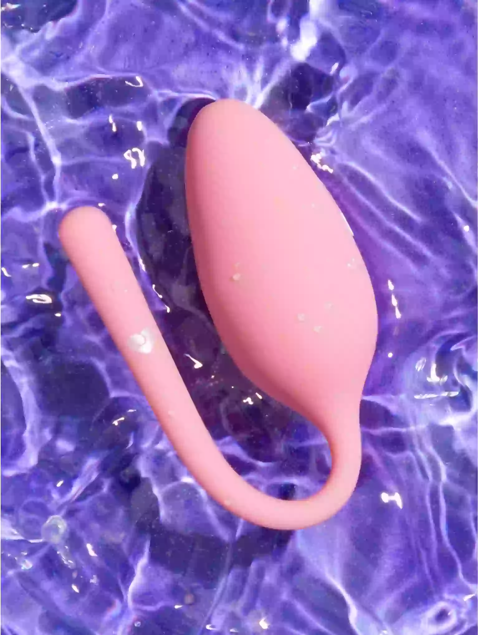 Pink silicone tool on a purple water-like background